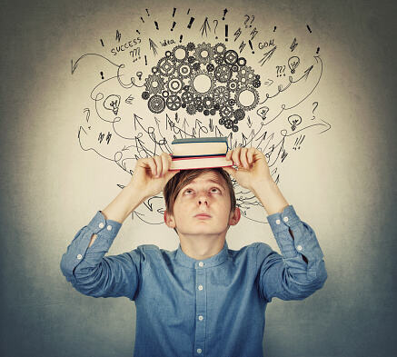 Boy holding books over his head representing The Adolescent Brain